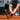 Tennis player in action on a clay court with a red racket.
